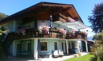 A beautiful house with a balcony adorned with flowers. The garden is green and well-maintained, perfect for relaxation.