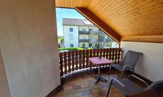 A cozy balcony with wooden walls and a table. Two chairs provide a nice spot to enjoy the view.