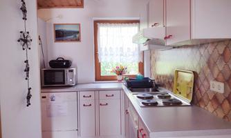 A bright kitchen with white cabinets and modern appliances. The window offers a view of a small flower on the windowsill.