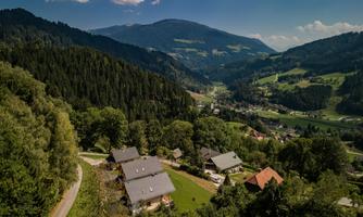 A picturesque landscape with gentle hills and typical buildings. Green forests and mountains surround the image, creating a serene atmosphere.