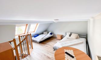 A bright room with two beds and a table. Large windows let in plenty of light.