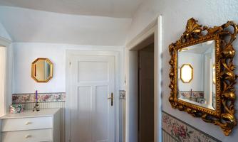 A friendly hallway with bright walls and antique mirrors. A dresser adds a charming character to the room.