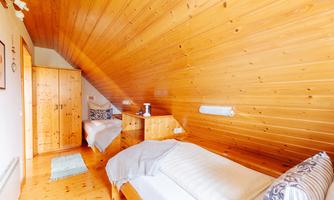 A cozy room with wood paneling and two single beds. On the wall, there is a wardrobe and some decorative elements.