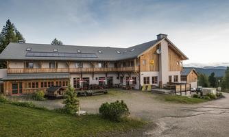 A charming building in a rural setting, surrounded by green meadows and trees. The façade is made of wood and offers an inviting atmosphere.