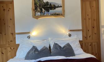 An inviting bedroom with a large bed and cozy pillows. A picture of a tranquil landscape hangs on the wall.