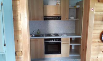 A modern kitchen with wooden shelves and appliances. The room is bright and cheerfully furnished.