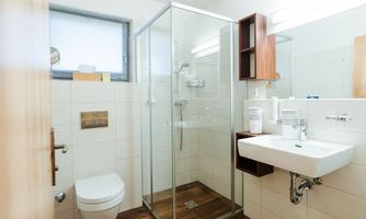 A modern bathroom with a glass shower and an elegant sink. The room has bright walls and wood-look tiles, creating an inviting atmosphere.
