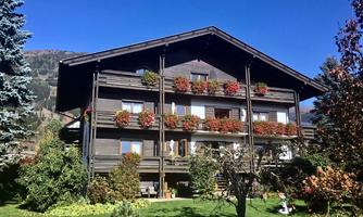A charming wooden house with flower boxes and balconies. The surrounding greenery and trees create an inviting atmosphere.