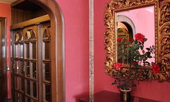 An elegant room with pink walls and a golden mirror frame. A beautiful bouquet of red roses adds a cozy touch to the ambiance.