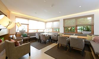 A modern waiting room with comfortable seating and large windows. There is a pleasant, inviting atmosphere and plenty of natural light.