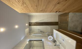A modern bathroom with a shower, a sink, and a large mirror. The walls are tiled in a light color, and the wooden door adds a warm atmosphere to the room.