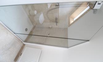 A modern bathroom with a glass shower and an additional skylight. The walls are designed in neutral colors and the atmosphere is bright and inviting.