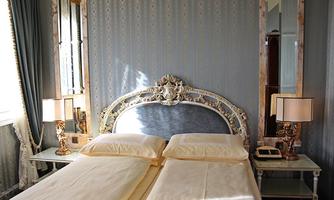 An elegant bedroom with two single beds and an artistic headboard. Delicate colors and stylish lamps create a cozy atmosphere.