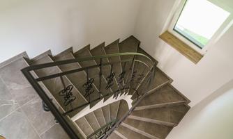 A curved staircase with an elegant railing. The room is bright and has a large window that lets light in.