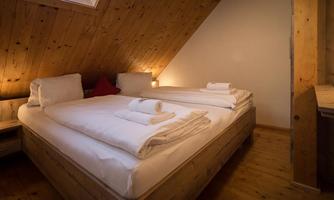 A cozy bedroom with a double bed and wooden decor. The atmosphere is warm and inviting, perfect for relaxing nights.