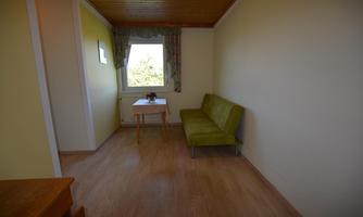 A bright room with a green sofa and a table. The window offers a view outside.