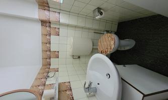 A small bathroom with a sink and a toilet. The walls are tiled and decoratively designed.