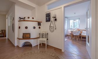 A bright entrance area with a beautiful stove and a cozy seating area. In the background, there is a dining area with a wooden table and chairs.