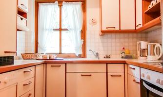 A bright kitchen with wooden cabinets and modern appliances. Windows let in a lot of light and give the room a cozy atmosphere.