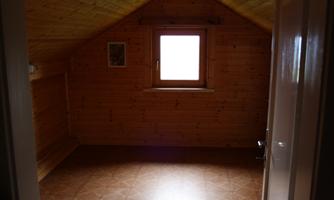 A bright, unfurnished room with wood paneling and a window. The floor is tiled.