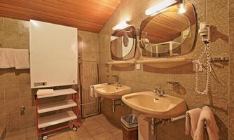 A bathroom with two sinks and large mirrors. The walls are equipped with tiled surfaces and wood paneling.