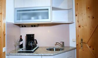 A modern kitchen unit with light cabinets and a granite countertop. A kettle and a coffee machine are placed on the counter.