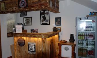 A rustic reception area with a wooden counter and several wall pictures. Next to the counter, there is a refrigerator with various drinks.
