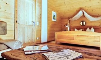 A cozy room with wooden paneling and a large bed. Several magazines are lying on a wooden table.