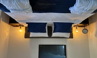 A comfortable bedroom with a large bed and blue pillows. The cozy atmosphere is complemented by bedside lamps and a wall mural.