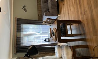 A cozy living room with a dining table and chairs. The window lets in plenty of light and the room has a warm, inviting ambiance.
