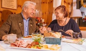 An older couple enjoys a meal together at a table. The atmosphere is cozy and friendly.