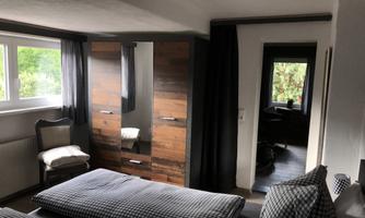A cozy bedroom view with two beds and a wooden wardrobe. The window lets in plenty of daylight and creates a bright atmosphere.