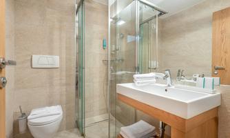 A modern bathroom with a glass shower and white sink. The room is bright and provides a pleasant atmosphere.