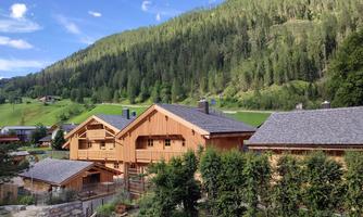 A picturesque mountain village with traditional wooden houses. The green hills and the blue sky create a relaxing atmosphere.
