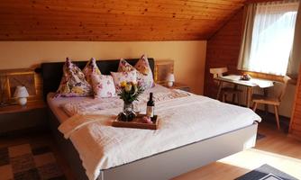 A cozy bedroom with a large bed and decorative pillows. A small table and a vase with flowers highlight the inviting atmosphere.