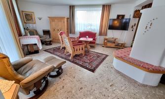 A cozy living room with comfortable seating and a large window that lets in plenty of light. The room is tastefully decorated with a rug and a stylish radiator.