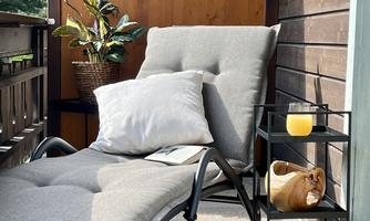 A cozy balcony with a deck chair and a small table. On the table is a glass with a drink and a plant creates a pleasant atmosphere.