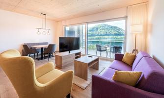 Bright living room with modern furniture and large windows offering a view of the mountains. The space is designed to be cozy and inviting.