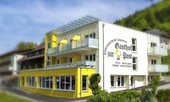 A modern inn with a yellow facade and large windows. It offers hotel rooms and a restaurant in a green setting.