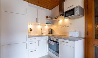 A modern kitchen with white cabinets and granite countertops. The equipment includes a stove, an oven, and a microwave.