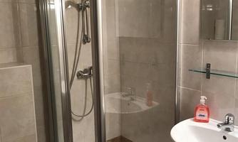 A modern bathroom with a shower cabin and a sink. The walls are brightly tiled and the lighting is friendly.