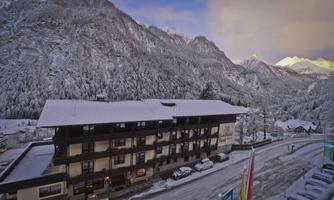 A charming hotel in the mountains, surrounded by snow-covered peaks. The landscape is serene and picturesque, ideal for winter vacation.