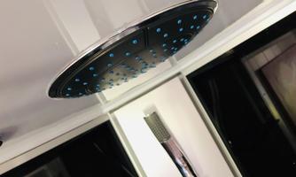 A modern showerhead design with blue LED lights. The shower is installed in an elegant room with glass walls.