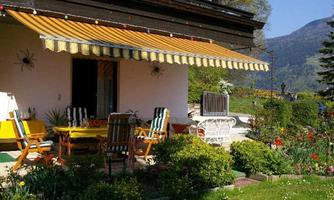 A cozy garden with a small terrace area. Surrounded by blooming plants and a picturesque mountain landscape.