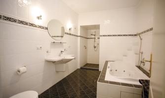 A modern bathroom with a white tiled floor and elegant fixtures. It is equipped with a shower, a bathtub, and a sink.