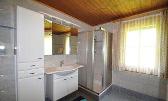 A modern bathroom with a glass shower and a sink. Bright colors and large windows create a friendly atmosphere.