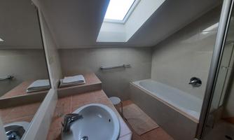 A modern bathroom with a bathtub and a sink. A large window provides plenty of natural light.