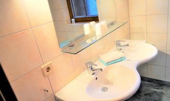 A modern bathroom with two sinks and a large mirror. The walls are brightly tiled and there are fresh towels.