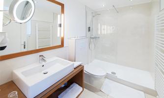 A modern bathroom with a shower and a stylish sink. The neutral colors and bright lighting create a pleasant atmosphere.