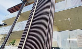 A modern residential building with wide balconies and an attractive facade design. The structure combines wood and concrete for an appealing appearance.